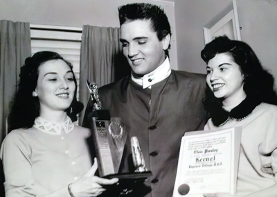 Elvis Presley is named an Honorary Kernel on the Mayor’s Staff of Popcorn Village for being the movie star whose movies sold the most popcorn. Louise, Cousin Gene Smith’s wife (left) Arlene Cogan, a member of The King’s Harem (right).